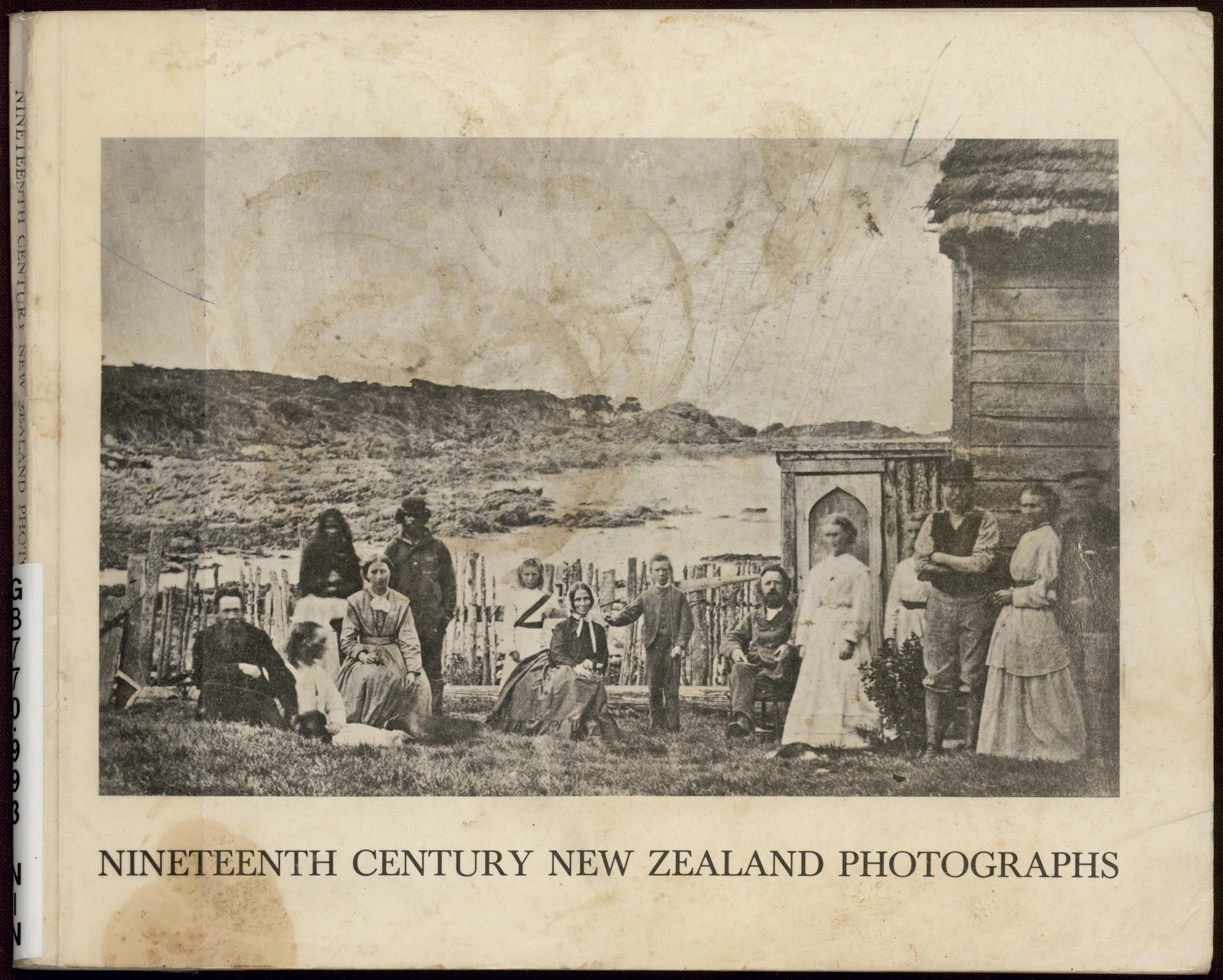Catalogue cover image, showing a black and white historical photograph of a group of people gathered next to a wooden building, with a coastal landscape in the background. 